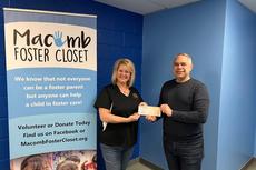 Groundworks holds a check with Macomb Forester Closet representative.