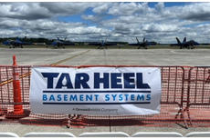 Four fighter jets parked on a runway behind a fence with a "Tar Heel Basement Systems" banner.