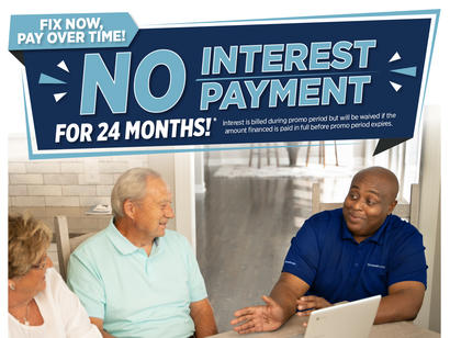A man in a blue shirt explains financing details to an older couple at a kitchen table. Text promotes no interest.