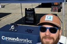 a Groundworks employee stands next to a company booth at the Roll'N Out Food Truck Festival in Grand Rapids