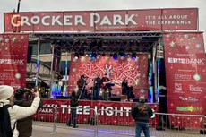 A band performs on an outdoor stage at Crocker Park’s Tree Lighting event, with people watching and taking photos.
