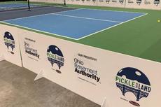 Indoor pickleball court with branding signs for Pickle in the Land and Ohio Basement Authority along the side.