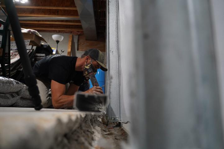 Crew installing full basment waterproofing and wall repair solution