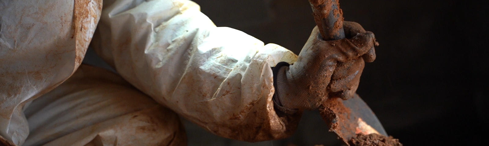 worker digging in crawl space with shovel