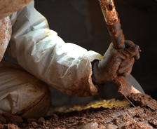 worker digging in crawl space with shovel