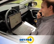 Man in a car taking notes on a laptop, smiling while on a phone call. "DRY-PRO" logo visible on screen and image.