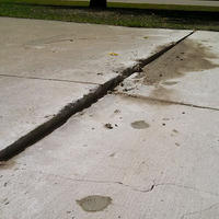 Close-up of an uneven sidewalk with a raised concrete slab creating a tripping hazard, highlighting the importance of understanding how to fix sinking concrete.