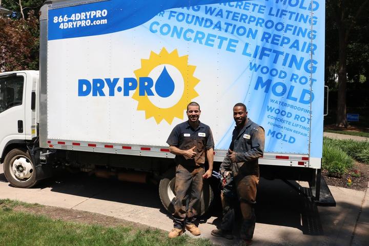 Two men stand in front of a Dry Pro truck.