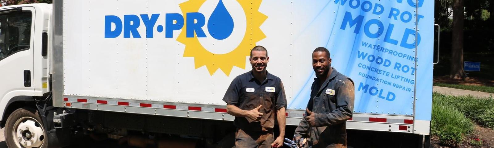 Two men stand in front of a Dry Pro truck.