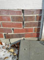 stair step crack in brick foundation next to garage door