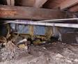 Fallen insulation and dirt in an unencapsulated crawl space
