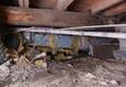 Fallen insulation and dirt in an unencapsulated crawl space