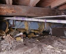 Fallen insulation and dirt in an unencapsulated crawl space