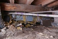 Fallen insulation and dirt in an unencapsulated crawl space