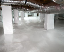 Crawl space with clean, white vapor barrier and insulated ducts running along the ceiling, showcasing how crawl space encapsulation can enhance home value.