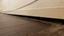Gap between a wooden floor and baseboard along a wall with visible wiring, often a sign of sagging floors.
