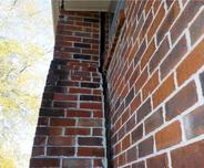 Red brick chimney separating from exterior wall