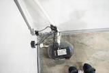 A sump pump system installed in a basement corner with visible cords and concrete floor.