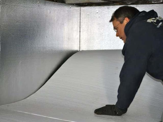 An Aquaguard Technician is installing floor insulation against an already insulated properly foundation wall.