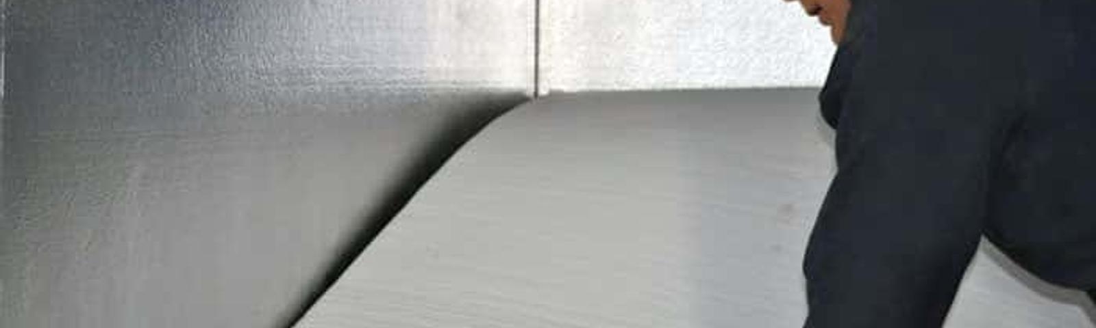 An Aquaguard Technician is installing floor insulation against an already insulated properly foundation wall.