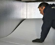 An Aquaguard Technician is installing floor insulation against an already insulated properly foundation wall.