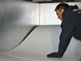 An Aquaguard Technician is installing floor insulation against an already insulated properly foundation wall.