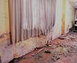 A damaged room with peeling walls, broken floorboards, and debris scattered across the floor hints at lingering basement humidity.