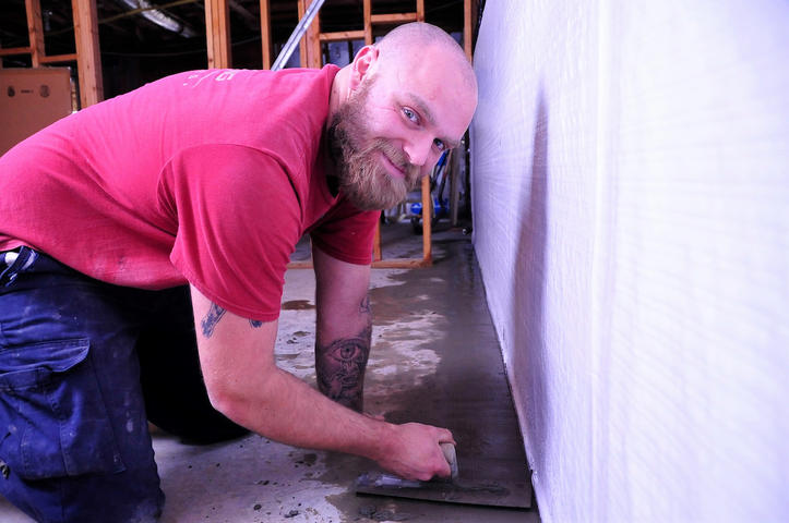 a worker installs a basementgutter around perimeter
