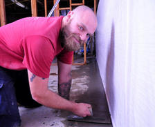 a worker installs a basementgutter around perimeter