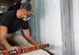 Crew using level during basement waterproofing and wall repair install