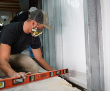 Crew using level during basement waterproofing and wall repair install