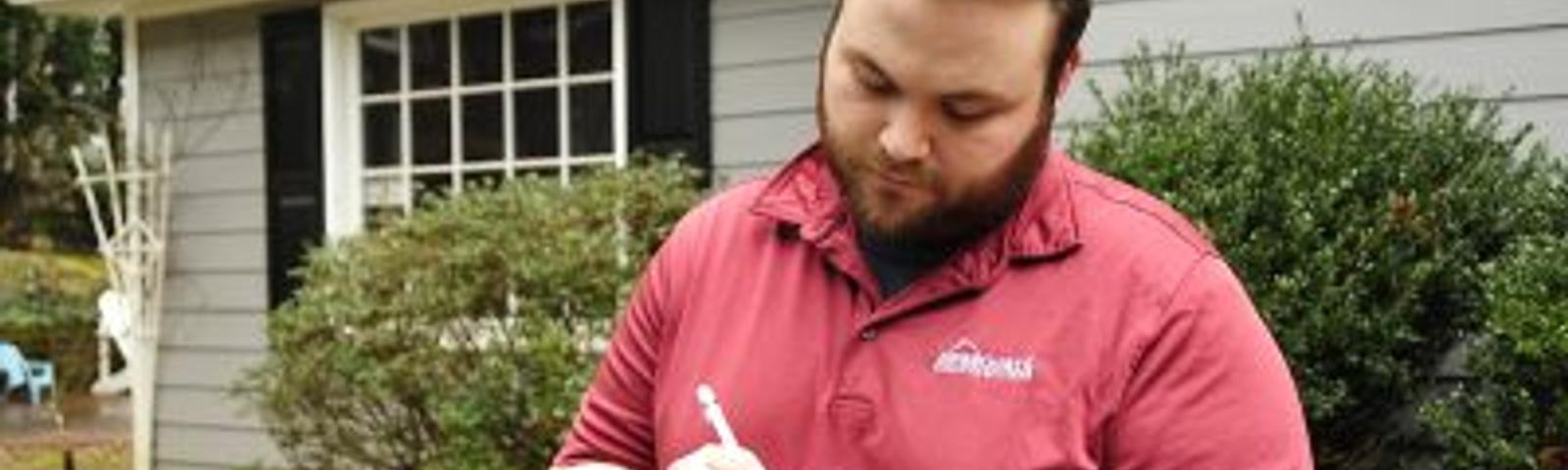 Certified Field Inspector taking notes outside a homeowners house