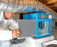Crew member installing dehumidifier into a crawl space