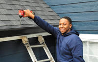 Worker on a ladder with power drill installing Aquastop Gutter Solution