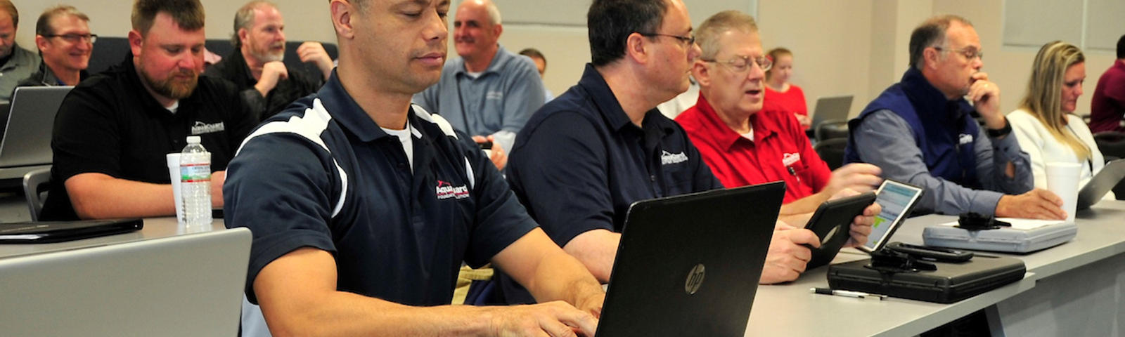 Workers sitting at tables with laptops for sales training
