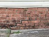 Red bricks on a house with stair step cracks due to foundation settlement