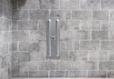 A wall anchor mounted in a previously cracked basement wall made of cinderblocks