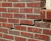 Red bricks on the exterior of a home with stair step cracks