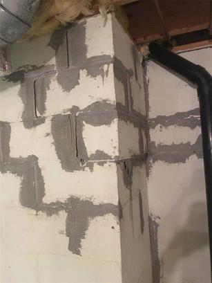 The results of a poor do-it-yourself basement wall repair project. The gaps in the cinderblocks were covered in spackle or cement to seal them, but the damage got worse, and so did the cracks.