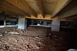 Dark, dirt floor crawl space with cinderblock supports