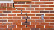 A large crack in the exterior brick of a home that the homeowner tried to fix on their own and it didn't work
