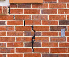 A large crack in the exterior brick of a home that the homeowner tried to fix on their own and it didn't work