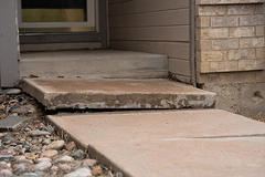 A very uneven slab of concrete sidewalk leading to the front door of someone's home