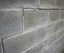 Cracked concrete blocks in a masonry wall, showing signs of structural damage.