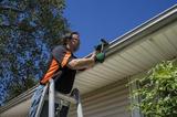technician nailing in gutters