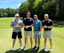 AquaGuard emplotees pose with golf clubs on a sunny golf course, trees and blue sky in the background. pose with golf clubs on a sunny golf course, trees and blue sky in the background.