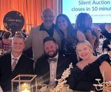 Five people dressed formally at a Wish Ball 2025 gala event, smiling at a table with candles and decorations.