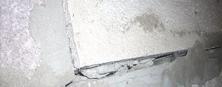 Close-up of a cracked and uneven concrete wall with visible layers and rough texture.