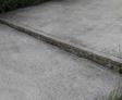A cracked concrete pavement with grass growing in the gap.