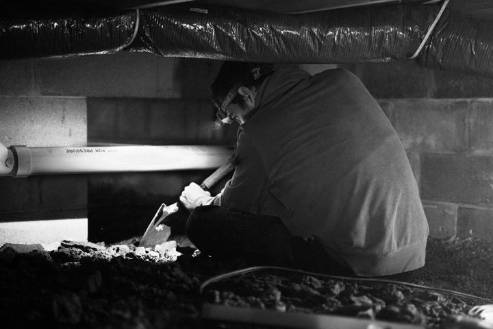crew member digging in crawl space